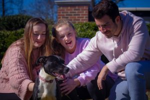 Photo of Sophia Surrett, Kate Merrill, and Luca Conti petting the dog Ikea