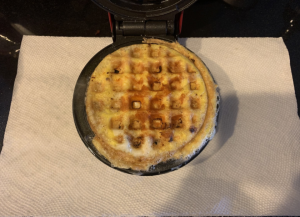 Egg and cheese cooking in waffle maker.