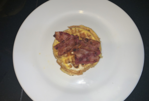 Egg and bacon cooked in waffle maker on plate